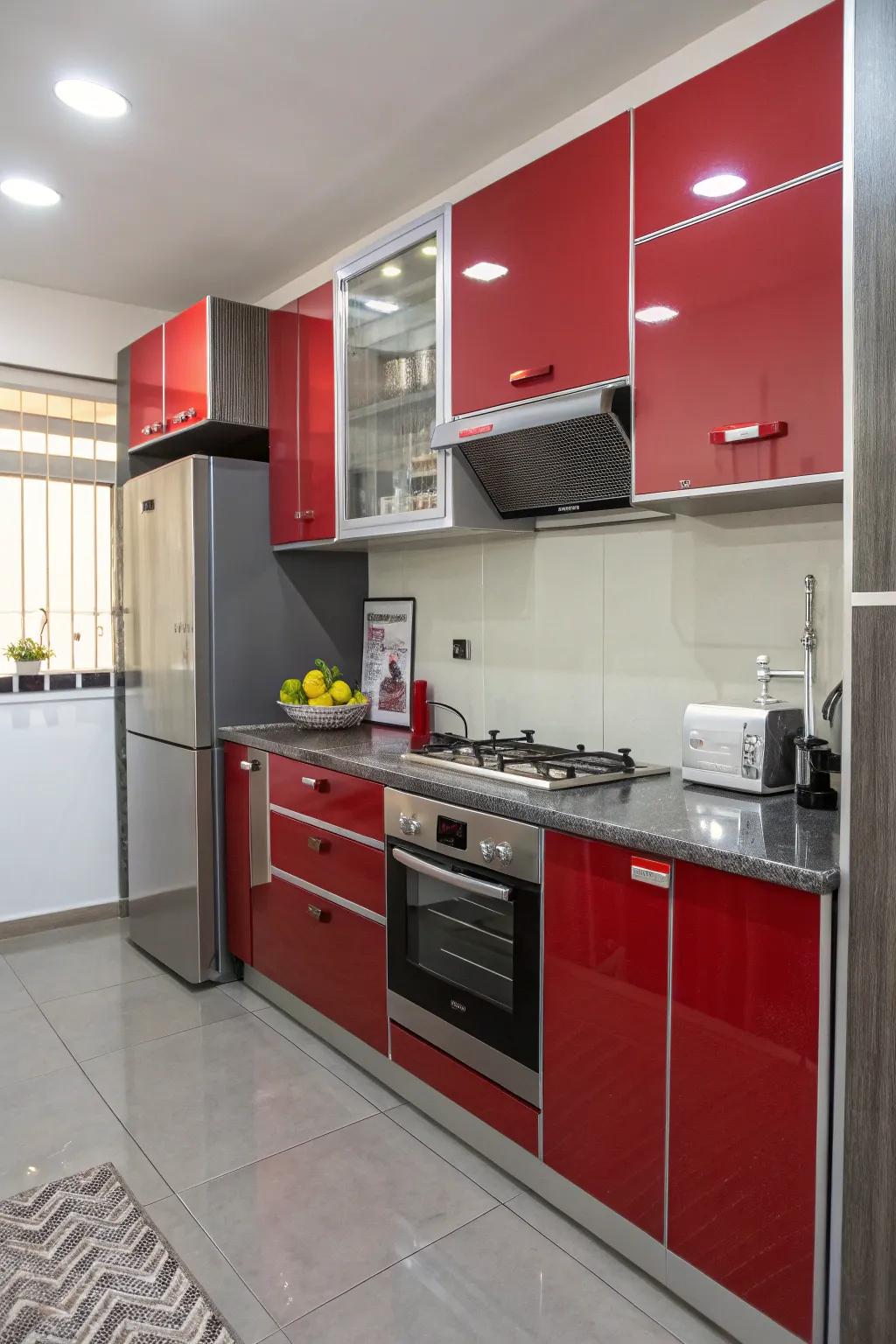 Shiny red and grey cabinets reflect light in a small kitchen.