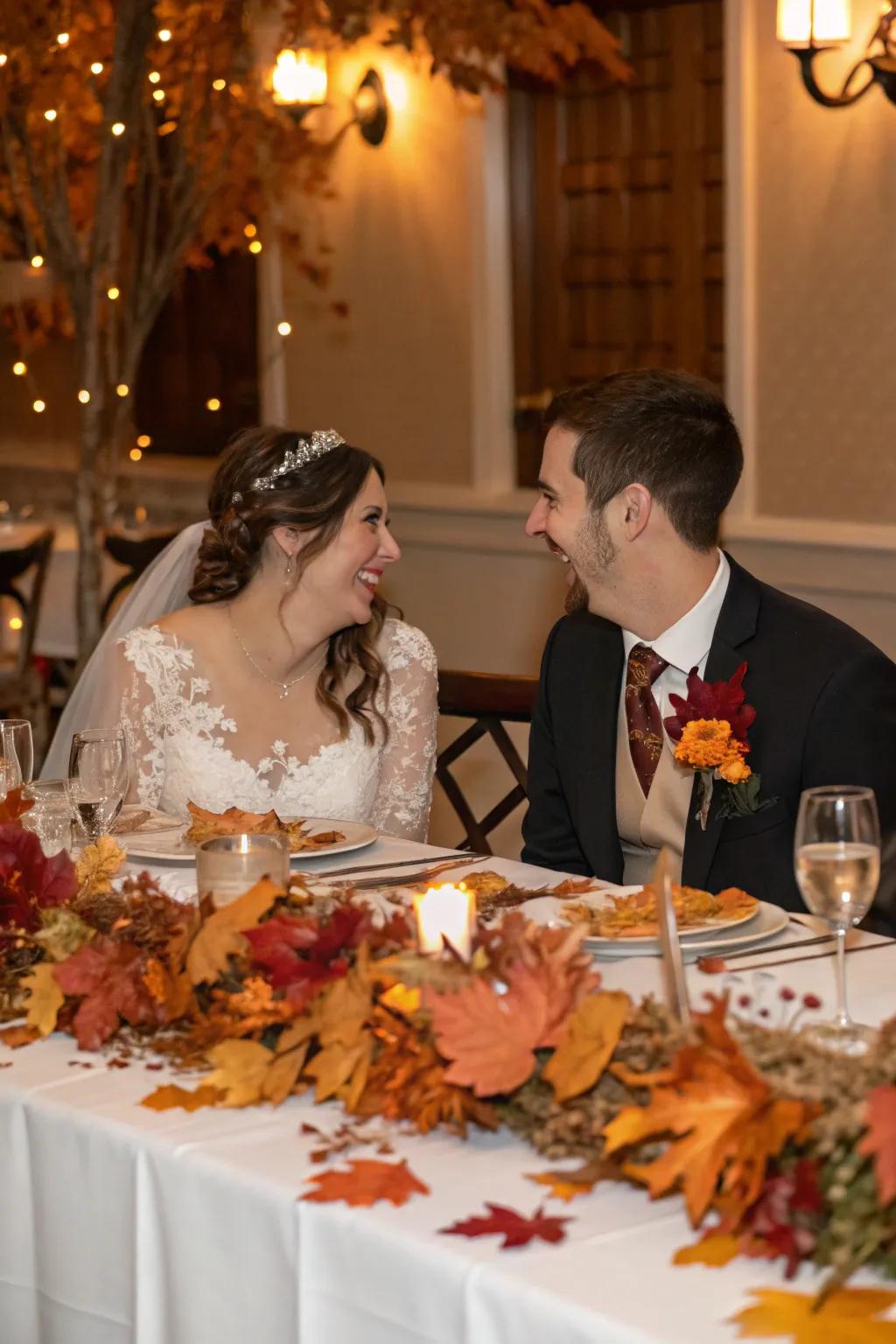 A bride and groom table decorated with seasonal decor like autumn leaves.