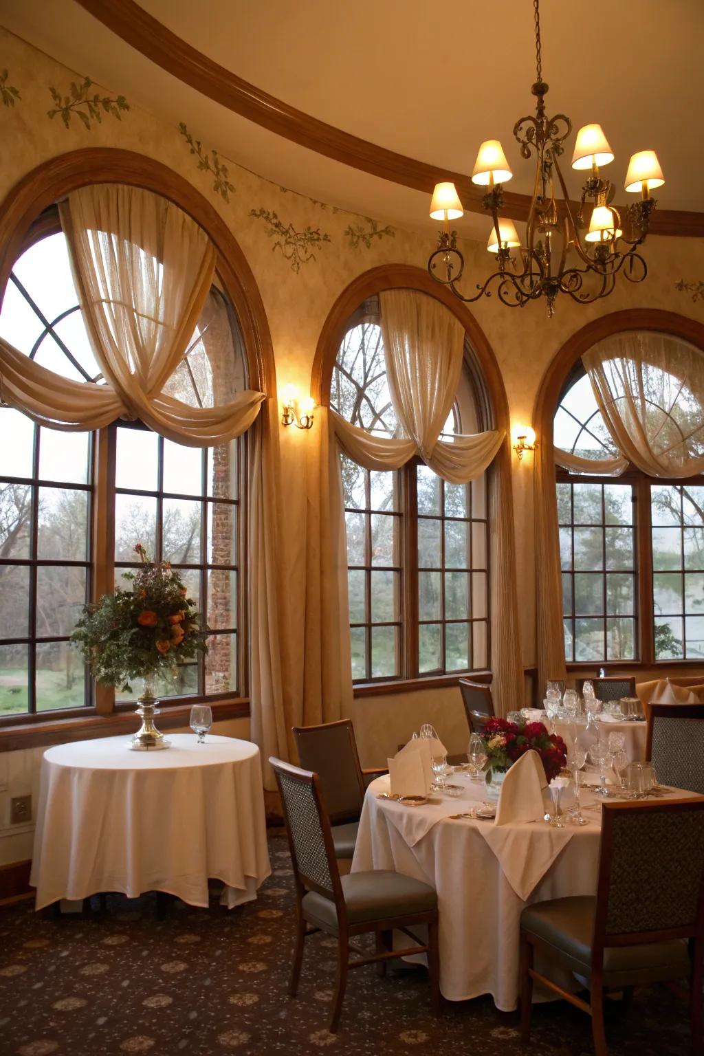 A romantic dining area showcasing draped cloth accents on arched windows.