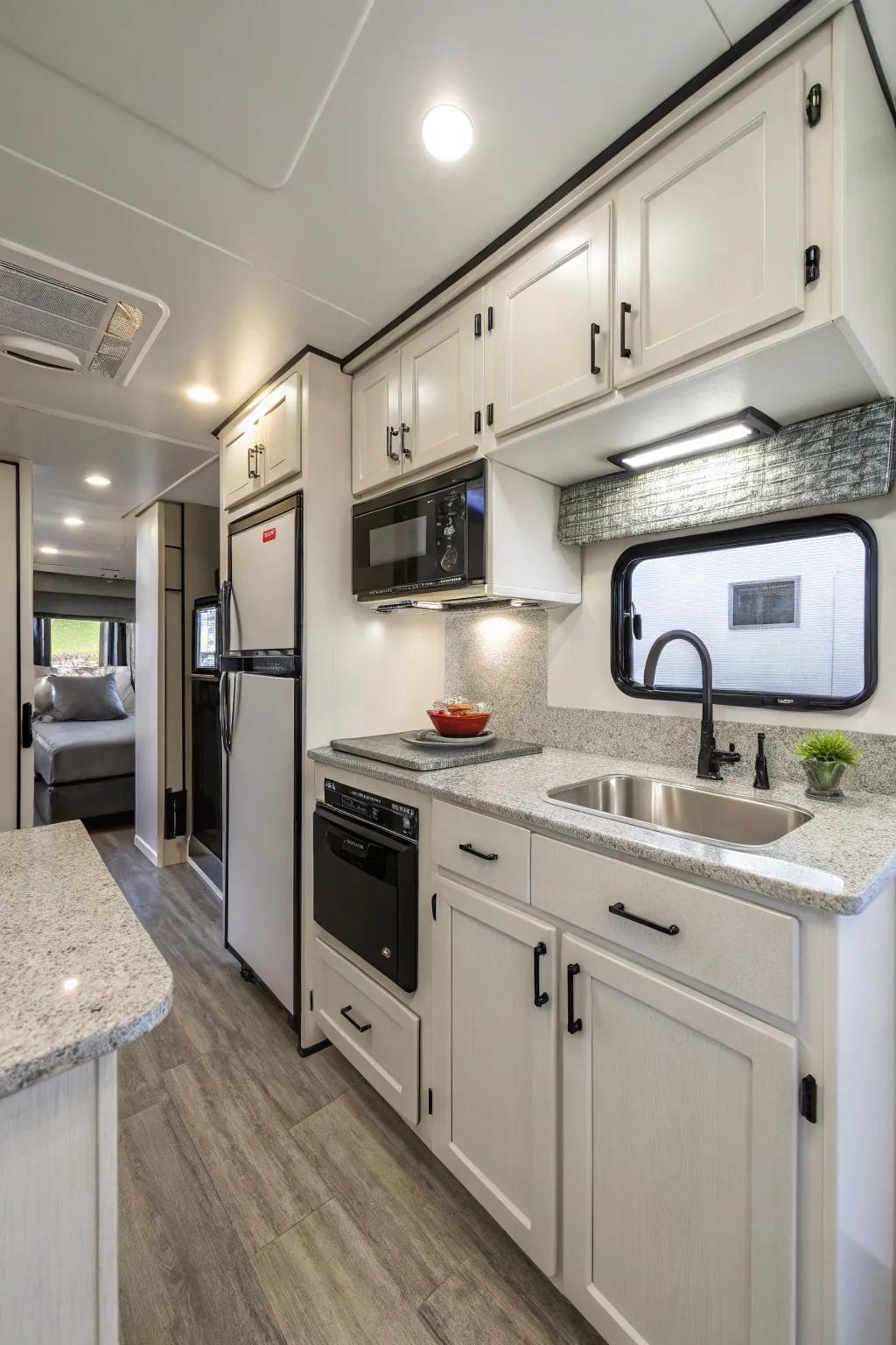 A modern kitchen in a travel trailer featuring neat cabinets and small appliances, great for making meals efficiently.