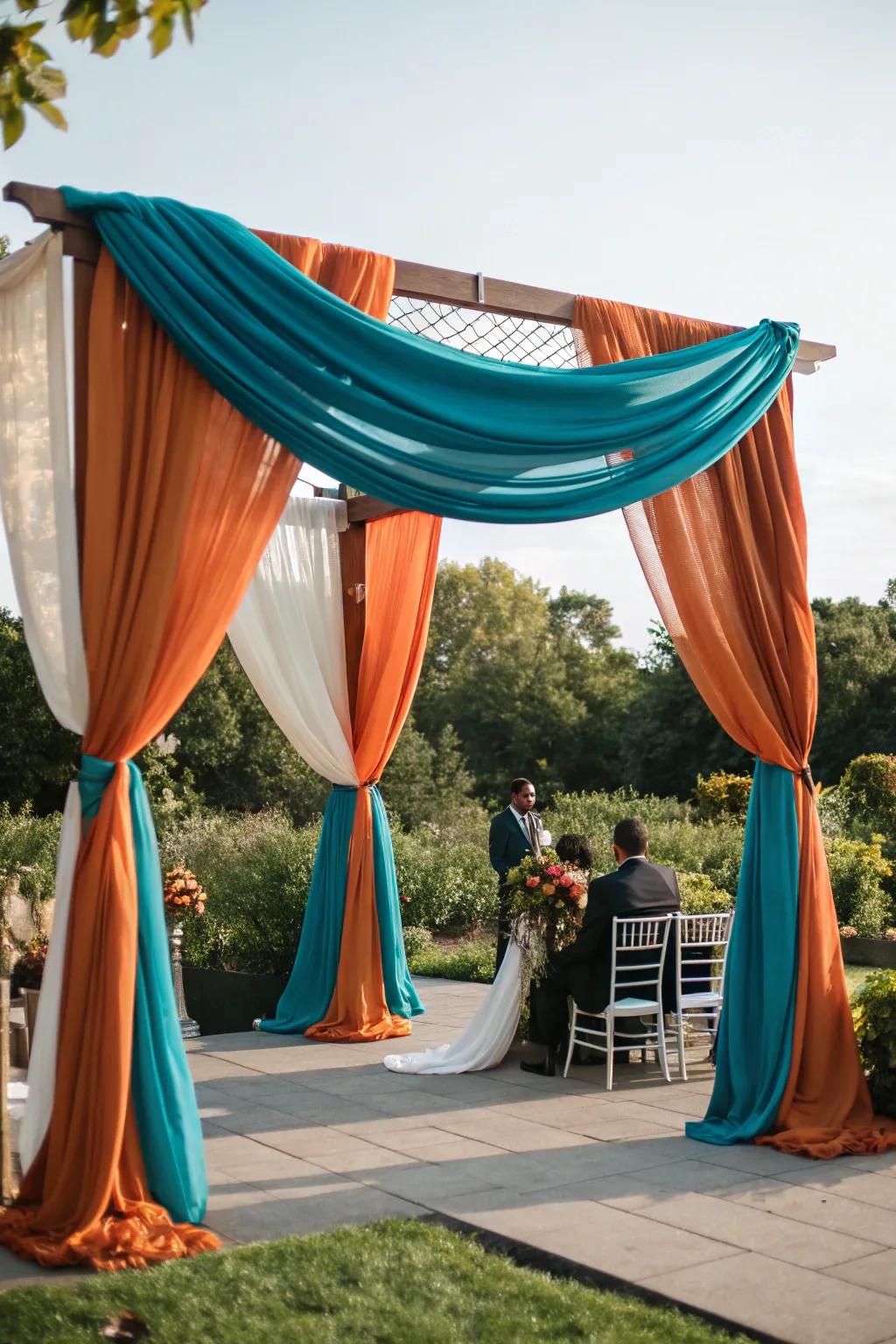 A ceremony archway draped in stunning cerulean and rust orange textiles.